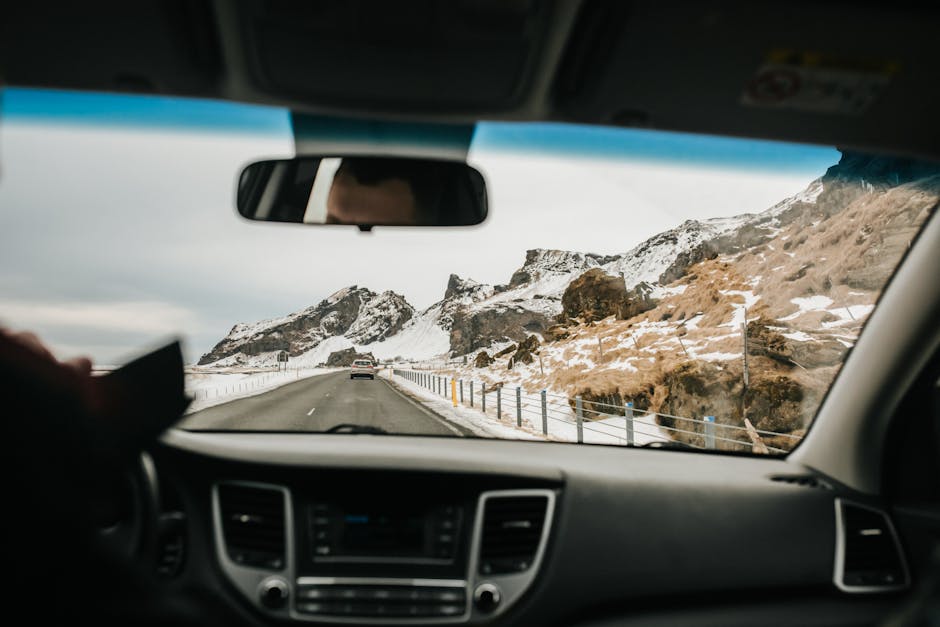 View from inside a car driving on a snowy mountain road, showcasing winter landscapes.